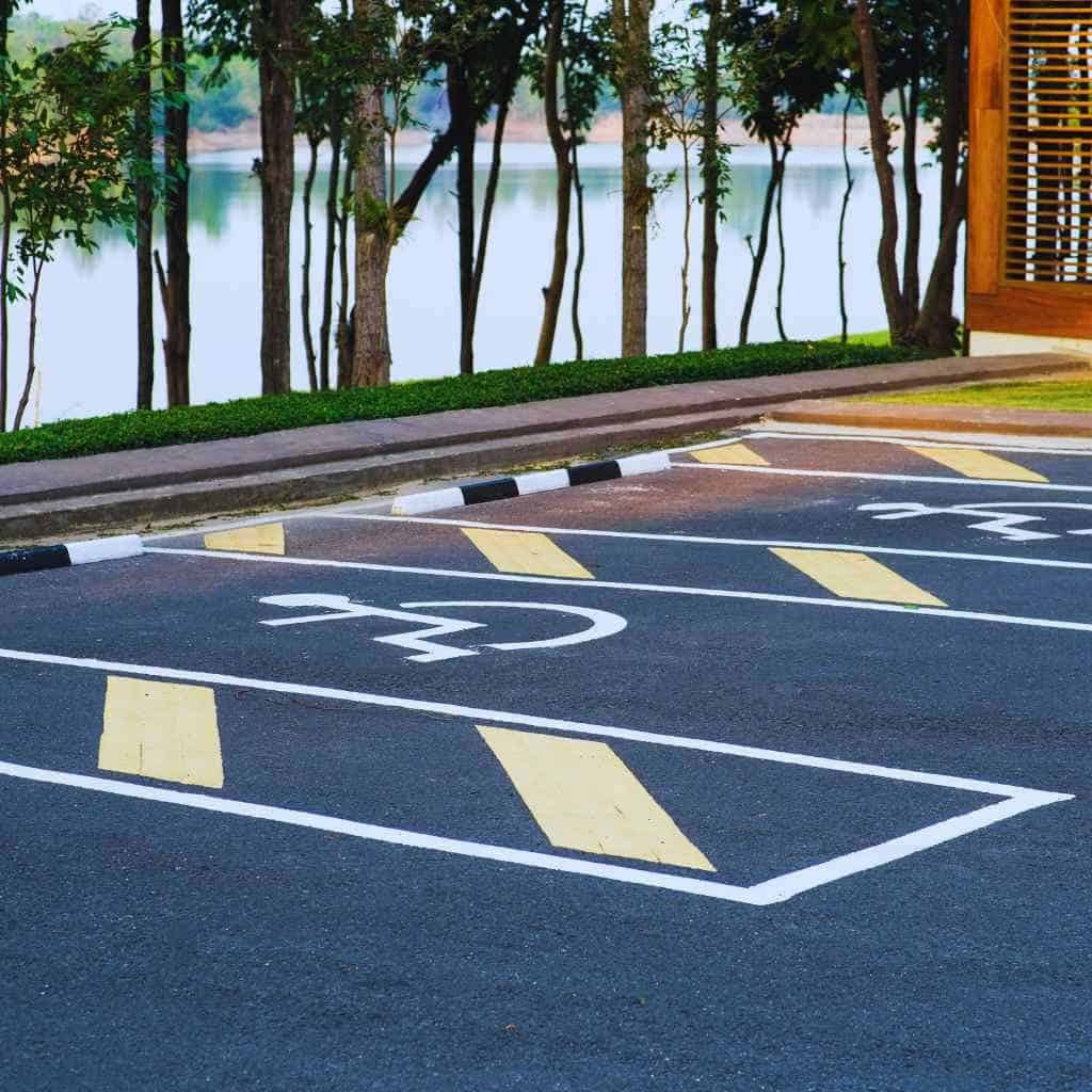 Striped accessible parking bays with cross-hatched access aisles, marked with wheelchair symbols and curb access, reflecting California Title 24 and ADA compliance design.