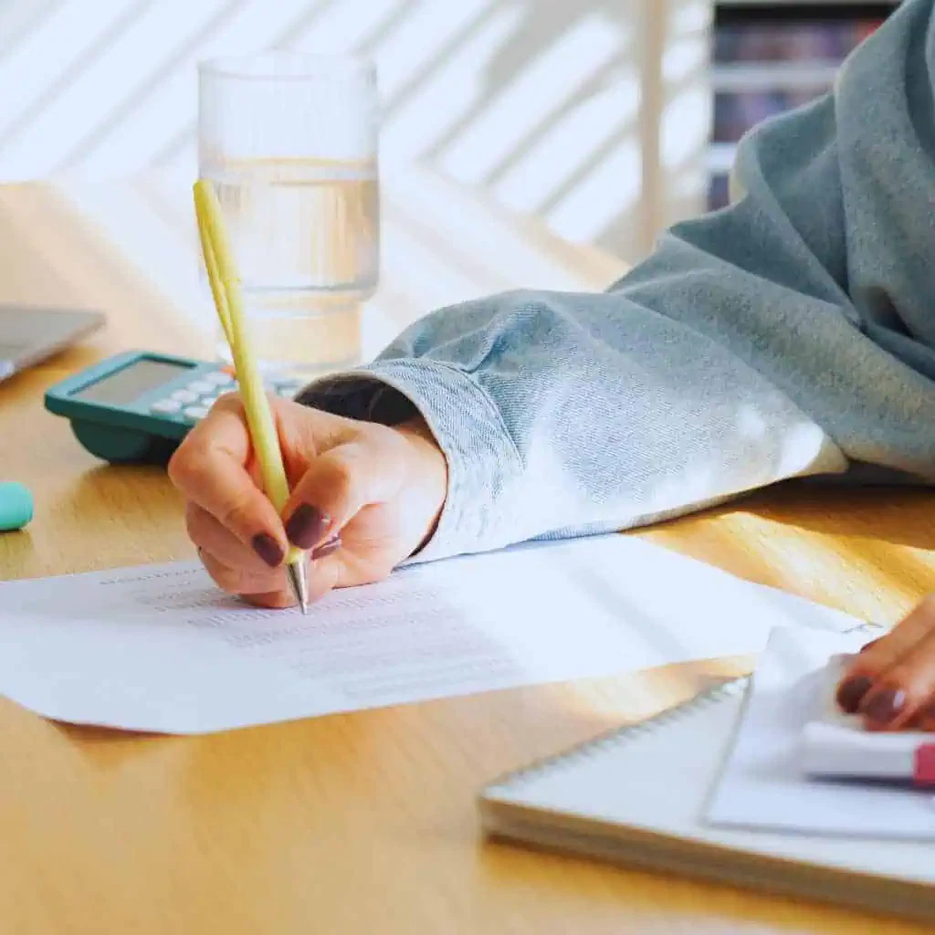 A person reviewing paperwork with a pen and calculator on the table, representing how California business owners prepare documents and estimate CASp inspection costs.