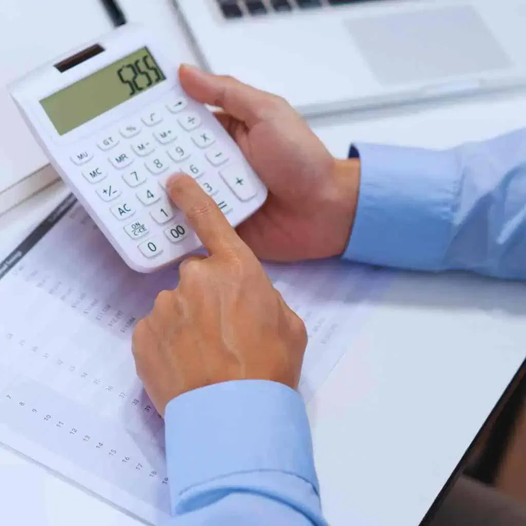 A property owner writing cost notes beside a calculator and inspection paperwork, illustrating how CASp inspection pricing depends on measurement scope and Title 24 requirements.