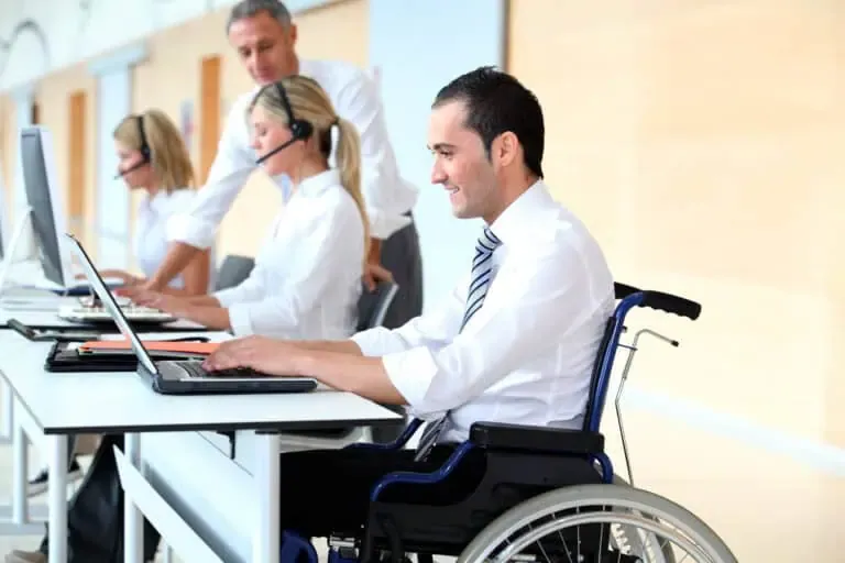 Professional man in wheelchair working at computer in an accessible office environment