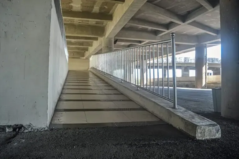 Indoor concrete ramp with railing showing steep incline and insufficient landing space