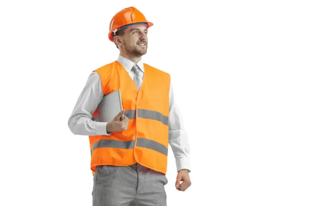 Smiling CASp inspector in orange safety vest and hard hat holding a tablet during an ADA accessibility site evaluation