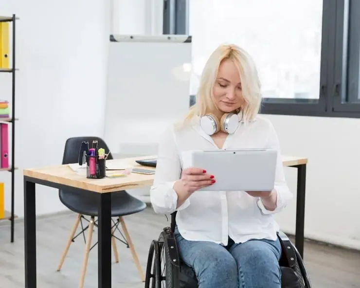 A woman in a wheelchair working on a tablet, representing challenges faced in non-ADA-compliant California government offices