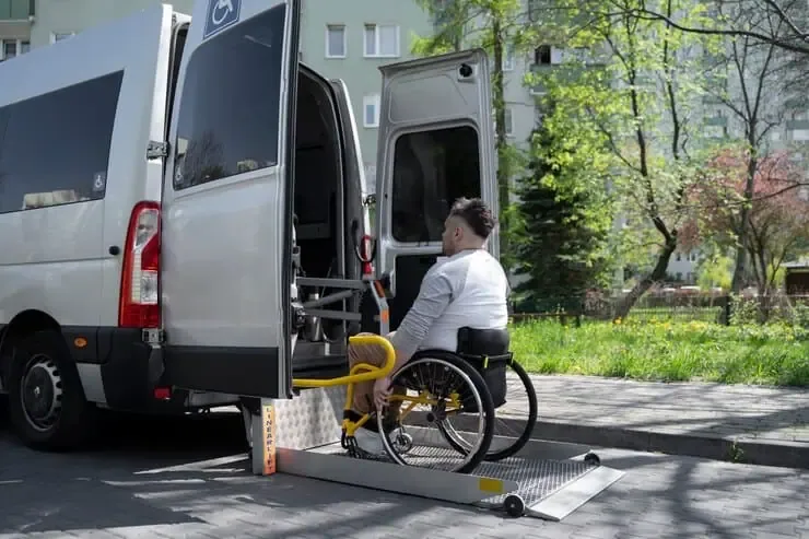 Man in wheelchair boarding accessible van using a side-entry hydraulic lift platform