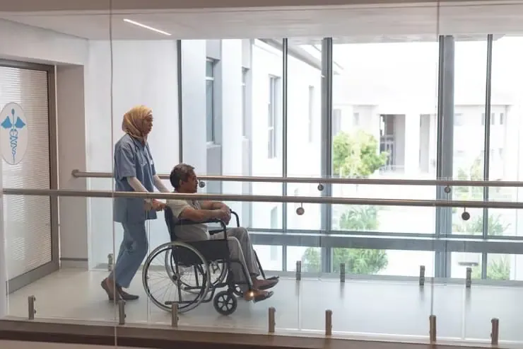 female doctor pushing male patient wheelchair corridor 13339 346572