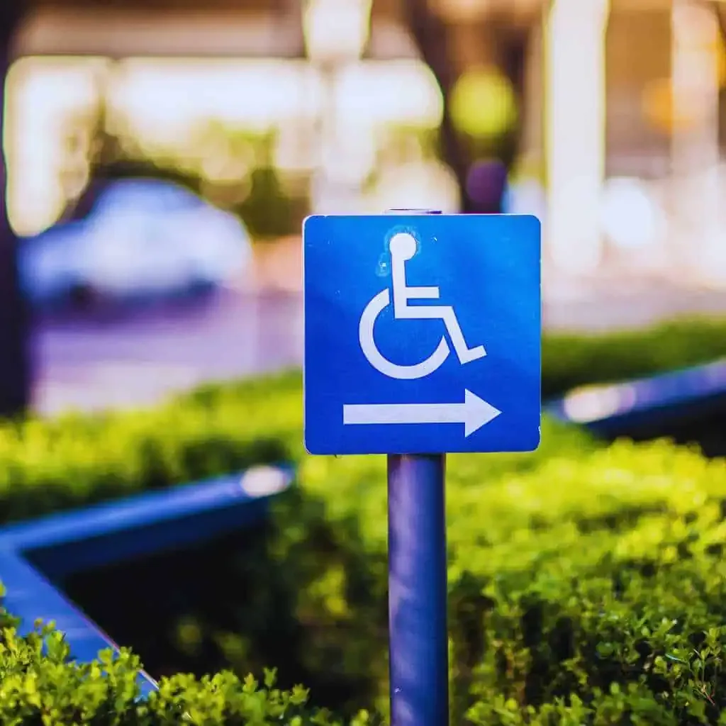 Fresno Businesses | Avoid ADA Fines with Annual Compliance Maintenance Plans 1 Blue wheelchair accessible sign with white arrow indicating accessible path in Fresno commercial area