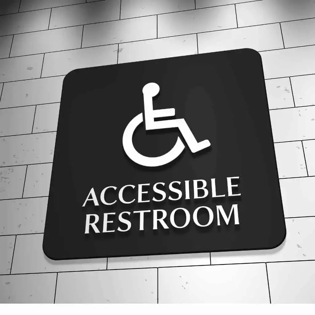 an accessible restroom sign mounted on a tiled commercial wall, showing the International Symbol of Accessibility used in CASp evaluations of restroom compliance.